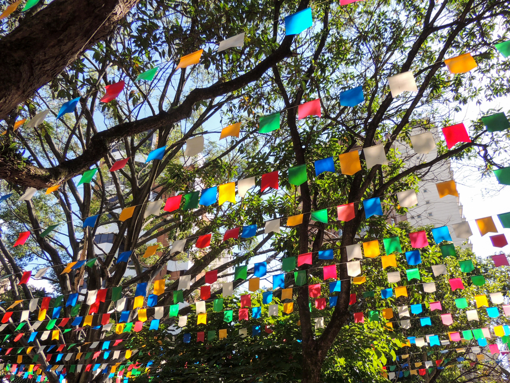 Bandeirinhas de festa junina penduradas entre árvores.