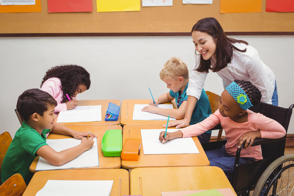 Professora fazendo o acompanhamento pedagógico de alunos em sala de aula.