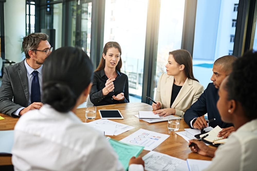 Reunião de negócios utilizando o inglês profissional para discutir estratégias em sala de conferências.