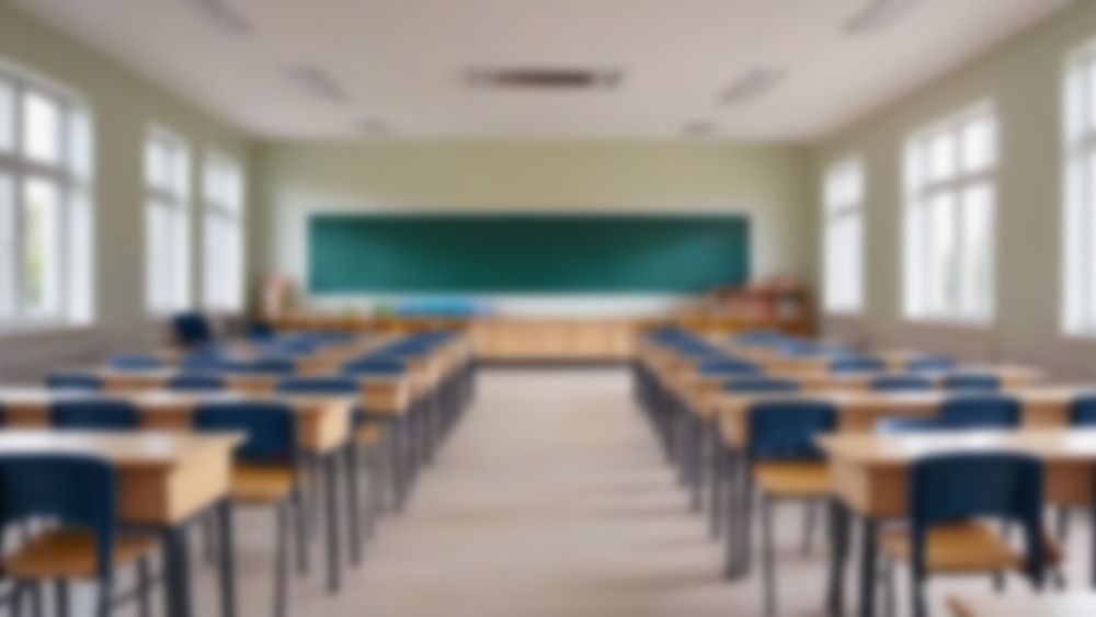 Sala de aula vazia, com carteiras organizadas em fileiras e lousa ao fundo.