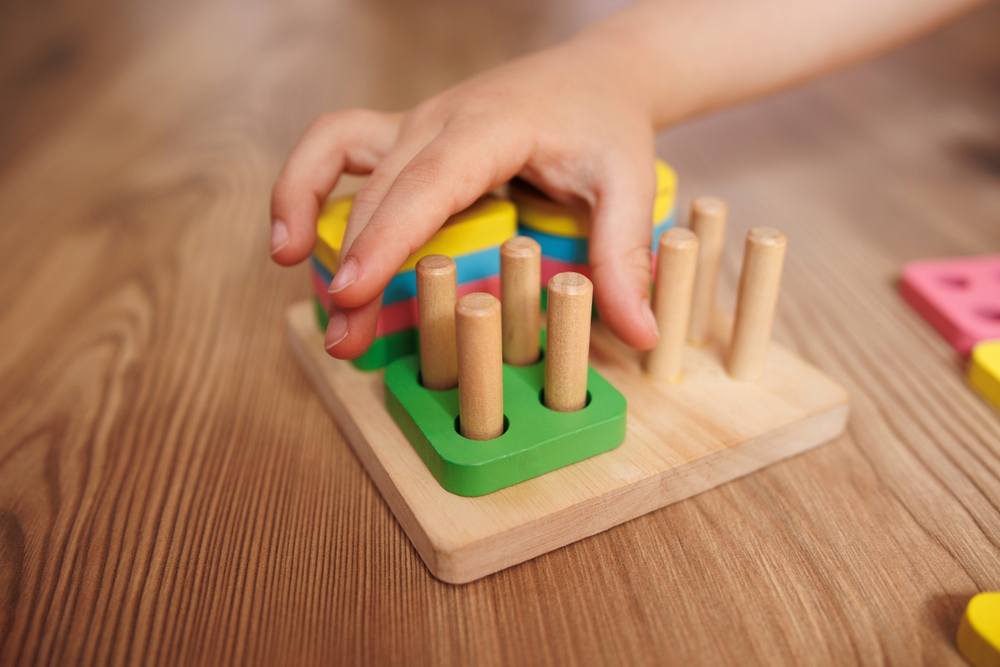 Mão de criança segurando e brincando com um brinquedo, representando a rotina da educação infantil.