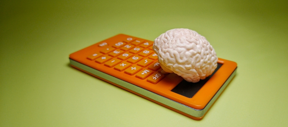 Calculadora com um cérebro em cima, simbolizando a relação entre lógica, raciocínio e resolução de problemas.