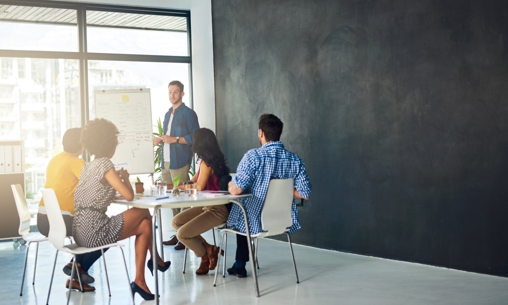 Imagem retrata um professor bilíngue ensinando alunos em sala de aula com planejamento de atividades. Remetendo-se ao processo de como fazer um planejamento de aula.