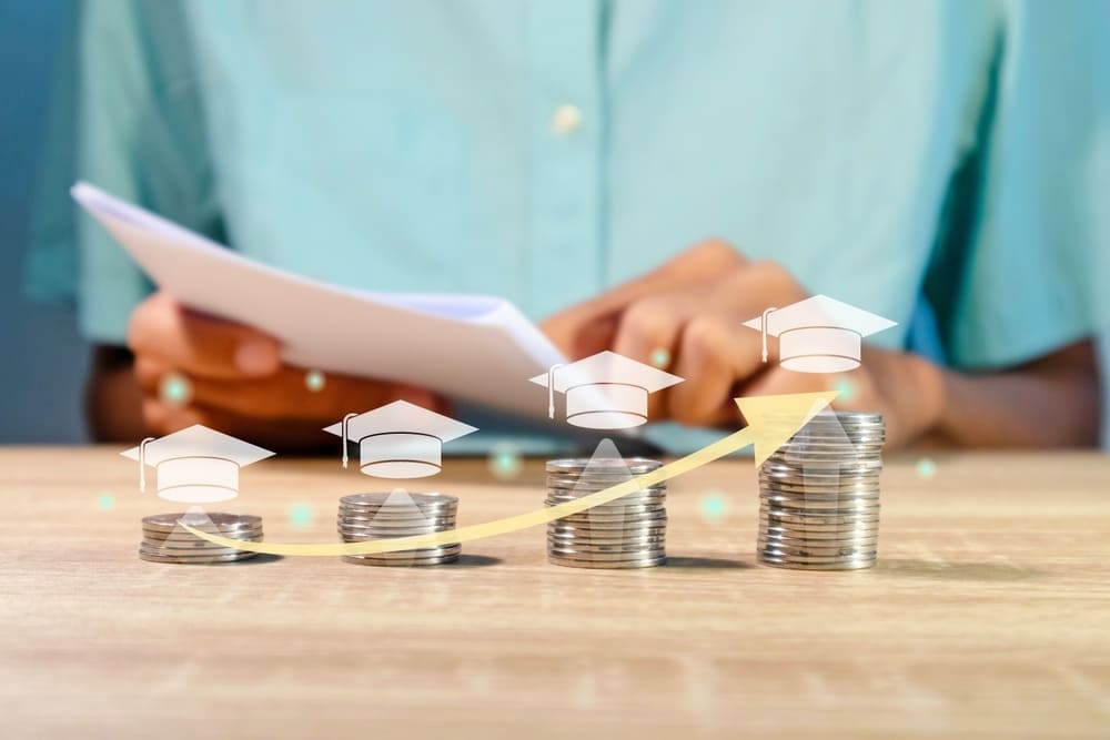 Pilhas de moedas em crescimento com ícones de formaturas e seta ascendente representando o aumento do ticket médio na escola.