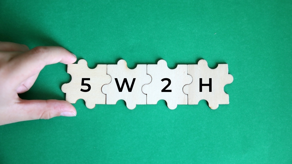 plano de ação 5W2H representado por blocos de madeira com a sigla 5W2H sobre uma mesa de trabalho.