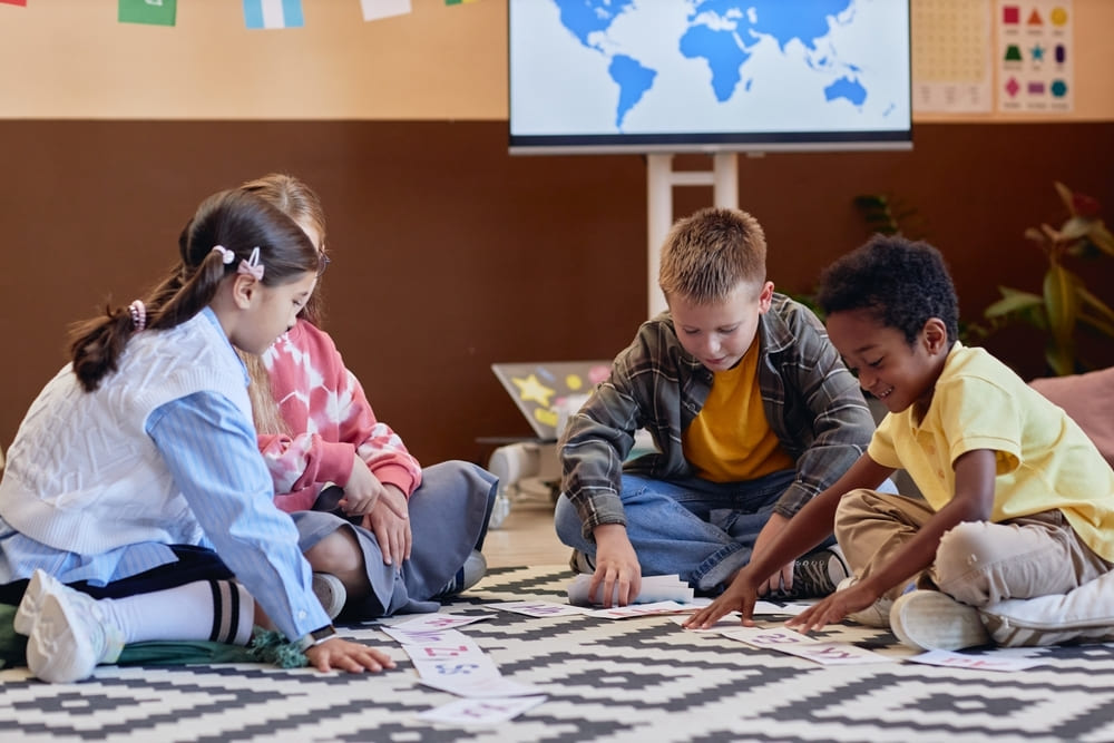 Crianças participando de atividade em grupo no chão da sala de aula, em momento de socialização e aprendizagem coletiva.