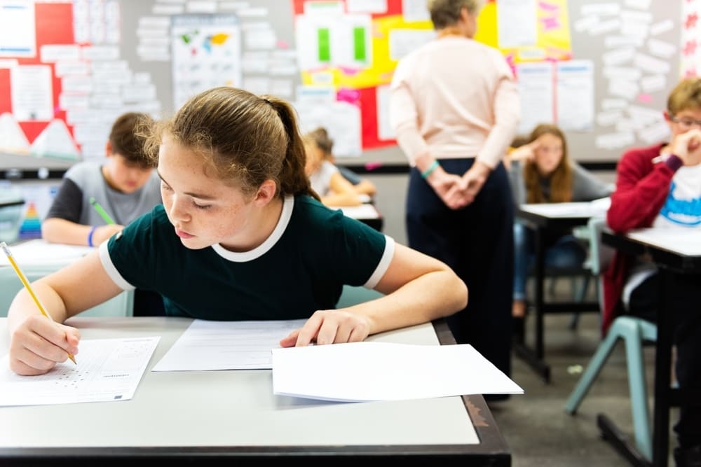 Aluna realizando prova em sala de aula, em momento de avaliação do desempenho acadêmico.