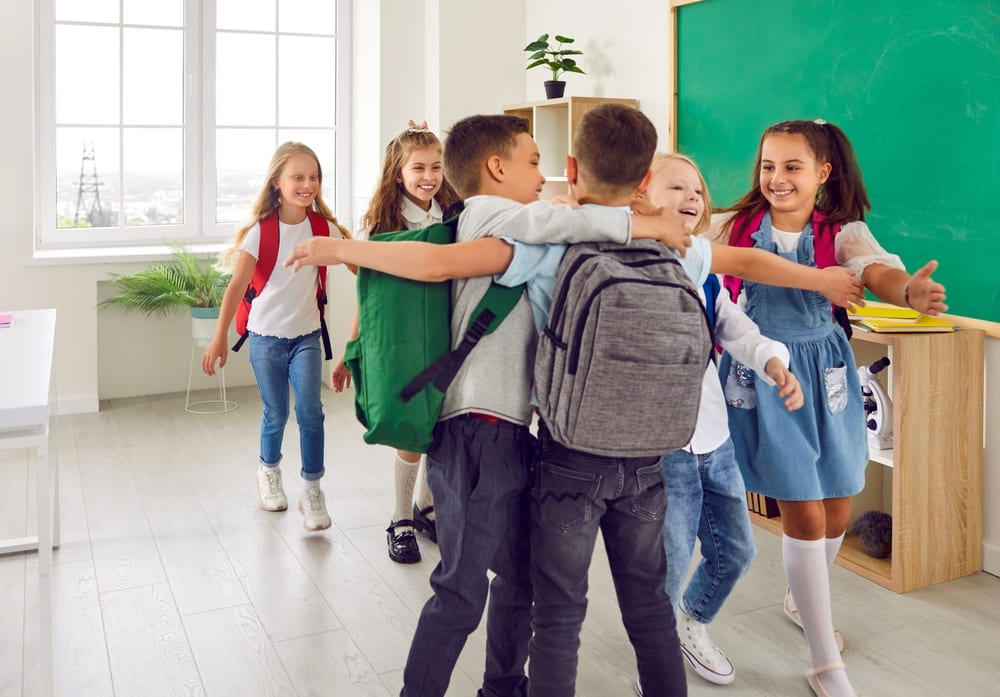 Crianças se abraçando em sala de aula, demonstrando empatia e amizade, em um ambiente escolar positivo e acolhedor, simbolizando a empatia na escola.