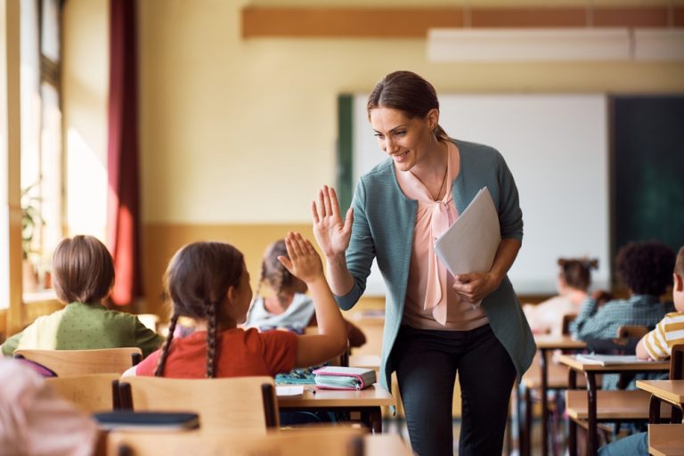 Professora e aluna dando um high five em sala de aula