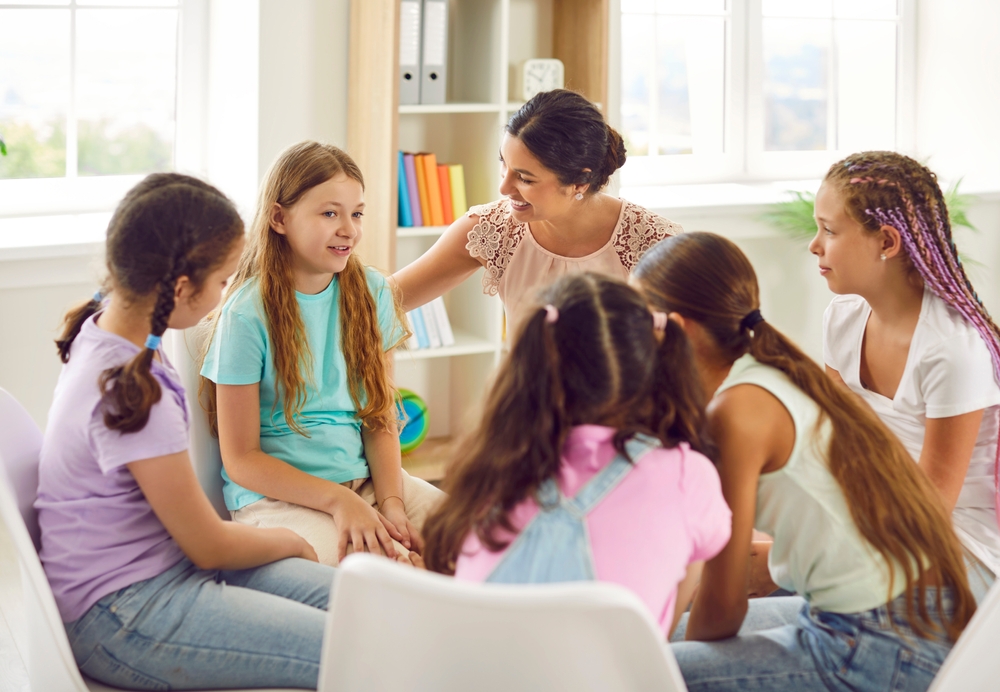 crianças em roda conversando com professora/psicóloga em uma sala