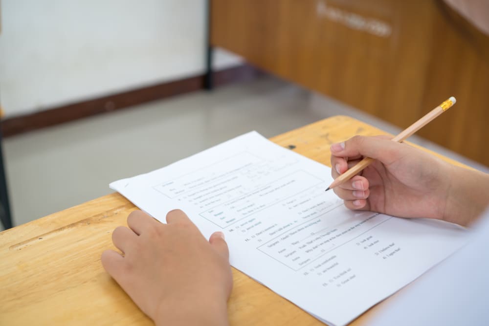 Estudante fazendo teste de proficiência em inglês com lápis e folha de respostas.
