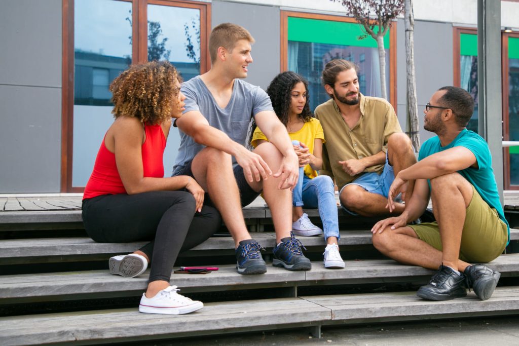 Grupo de jovens estudantes conversando ao ar livre, discutindo sobre seus projetos de vida e planos futuros.