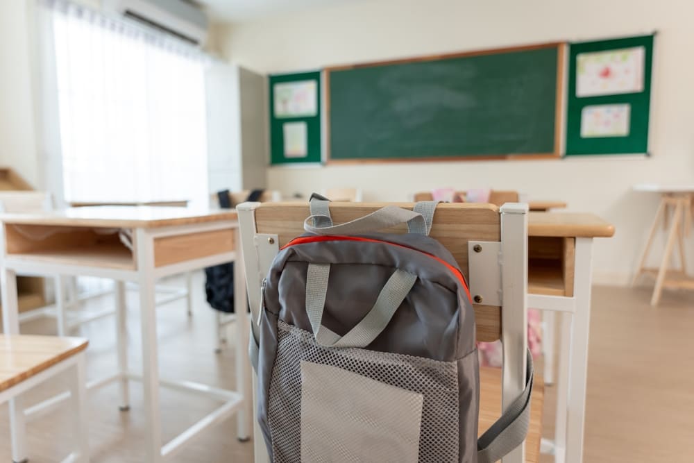 Infraestrutura da escola em sala de aula: iluminação natural, carteiras ergonômicas e lousa ao fundo.