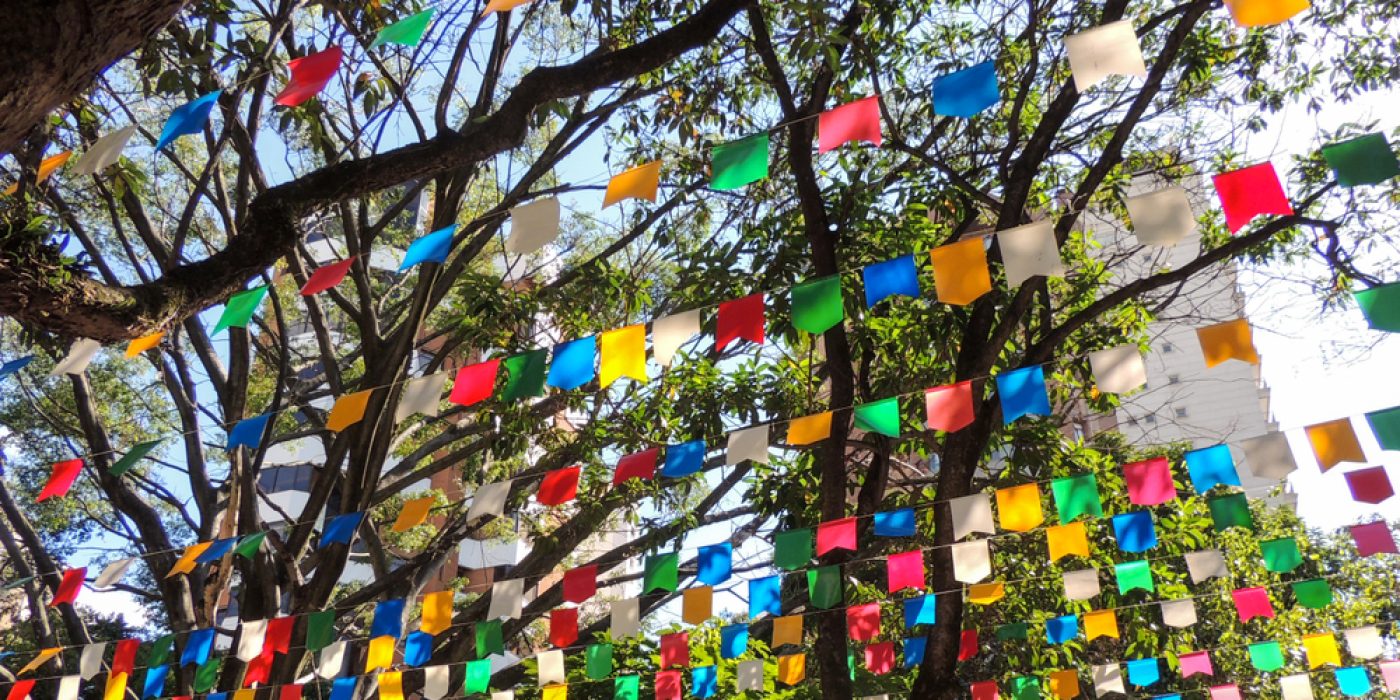 Bandeirinhas de festa junina penduradas entre árvores.