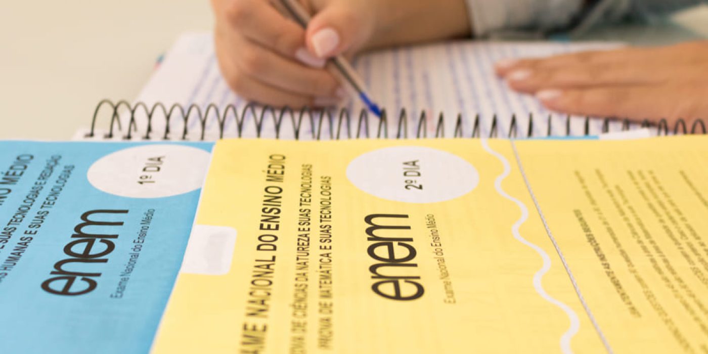 Cadernos do Enem com estudante escrevendo anotações durante os estudos.
