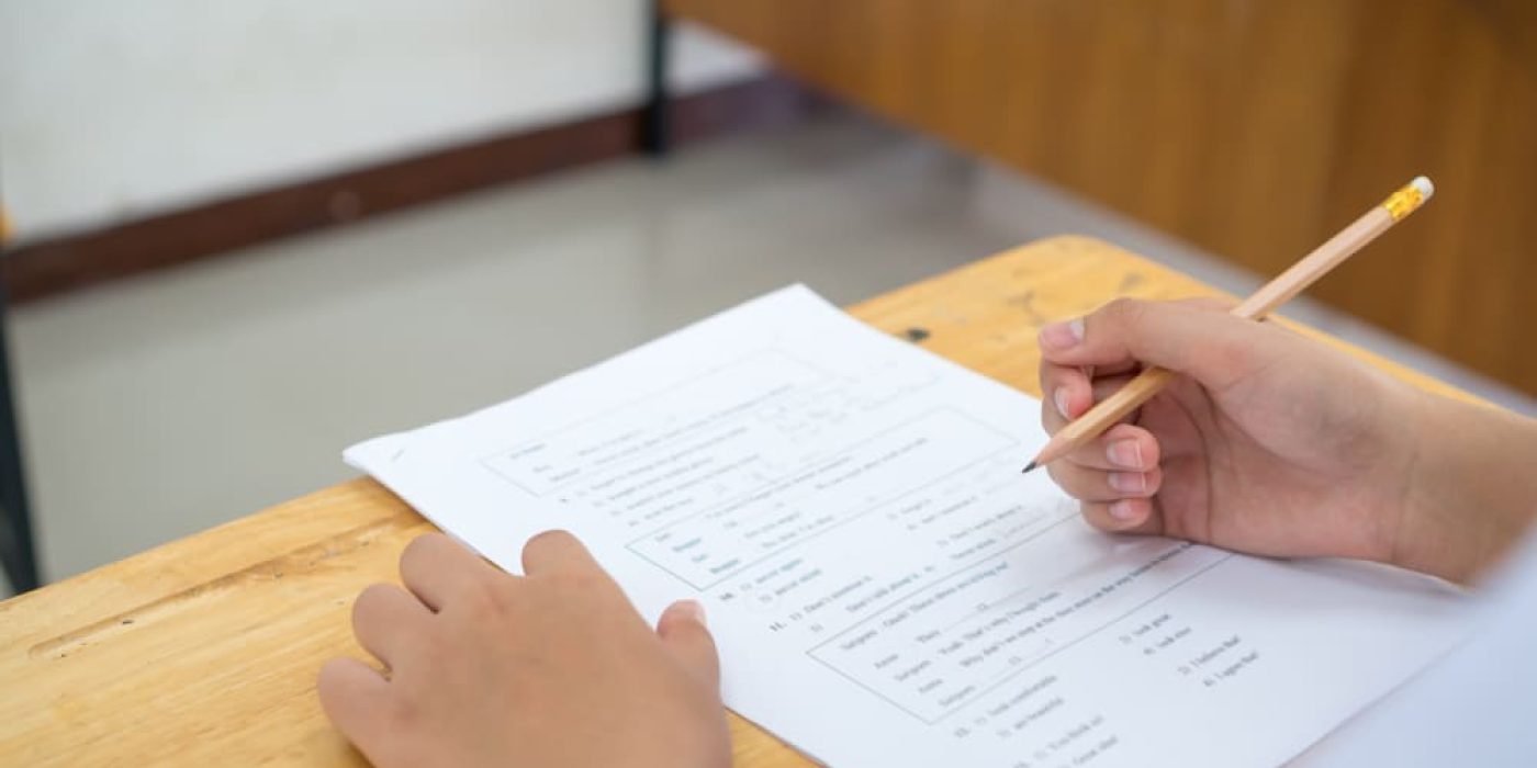 Estudante fazendo teste de proficiência em inglês com lápis e folha de respostas.