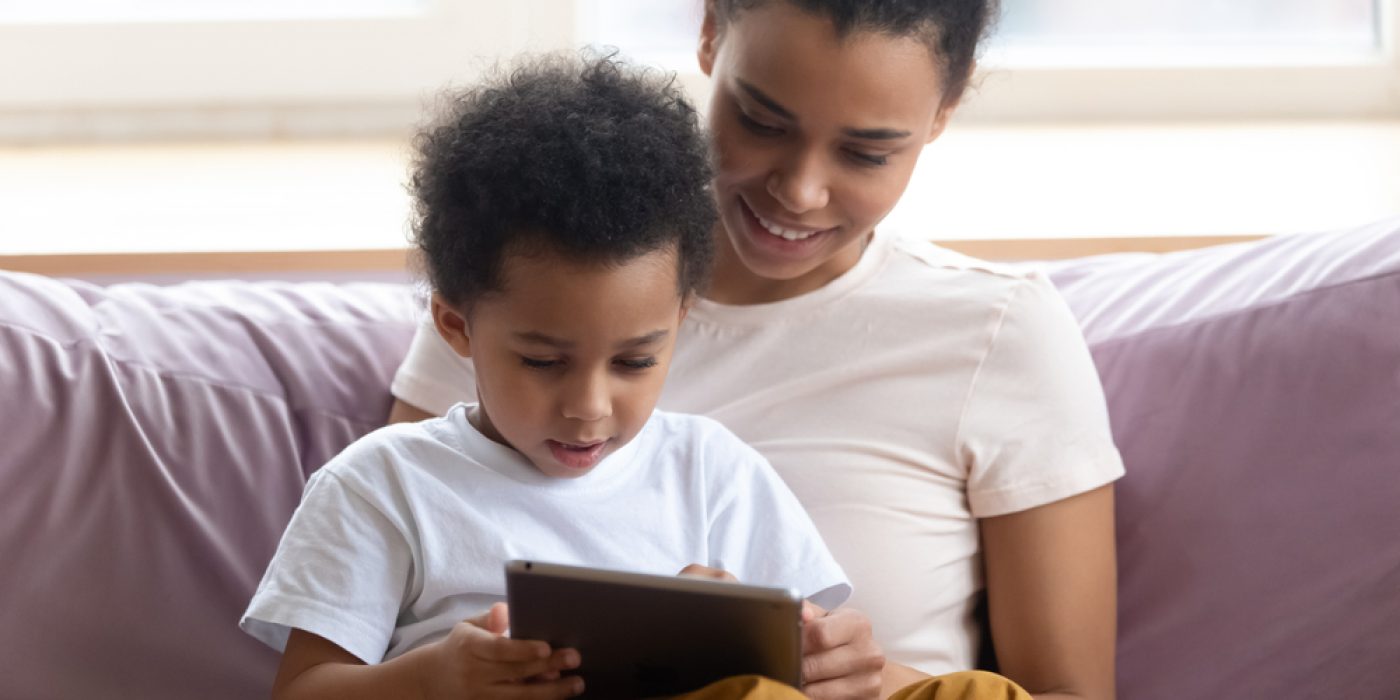 Mãe sentada no sofá com filho no colo usam tablet juntos