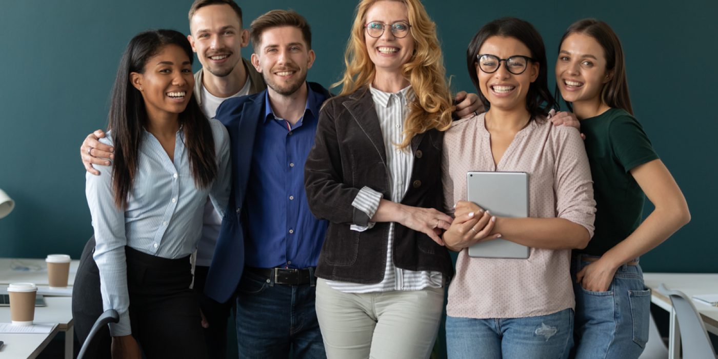 Grupo de professores e professores posa para foto em frente ao quadro de giz, sorrindo.