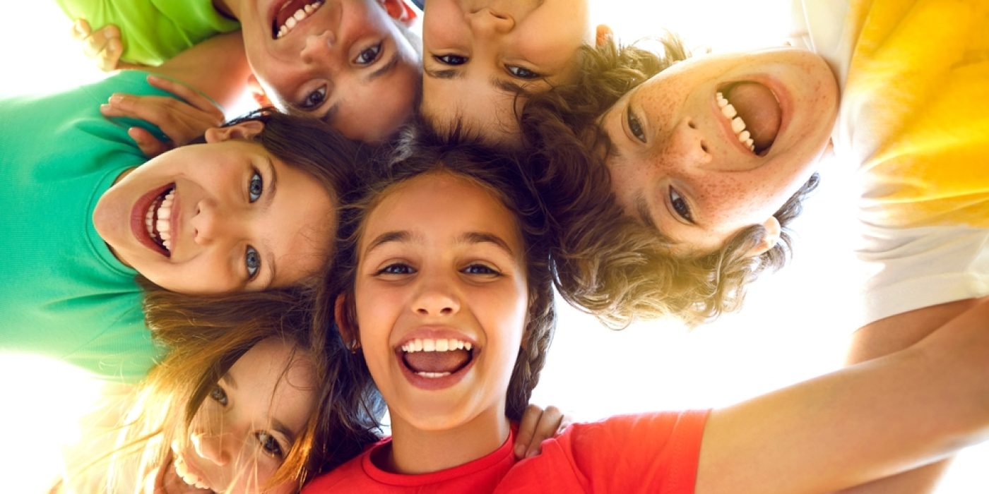 crianças sorrindo para a câmera, localizada debaixo para cima.