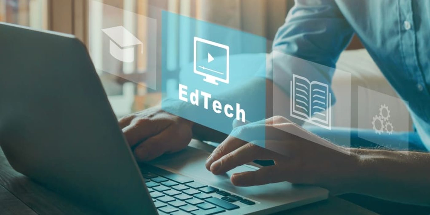 Mãos em laptop com ícones flutuantes representando edtech e ferramentas educacionais digitais.