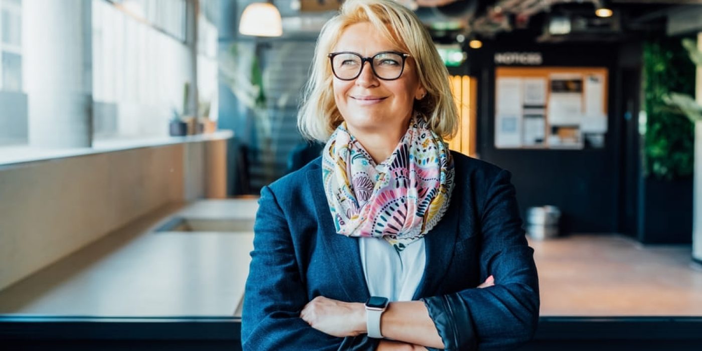 Gestora experiente, com braços cruzados, demonstrando confiança, em um contexto relacionado à gestão escolar de programa bilíngue.