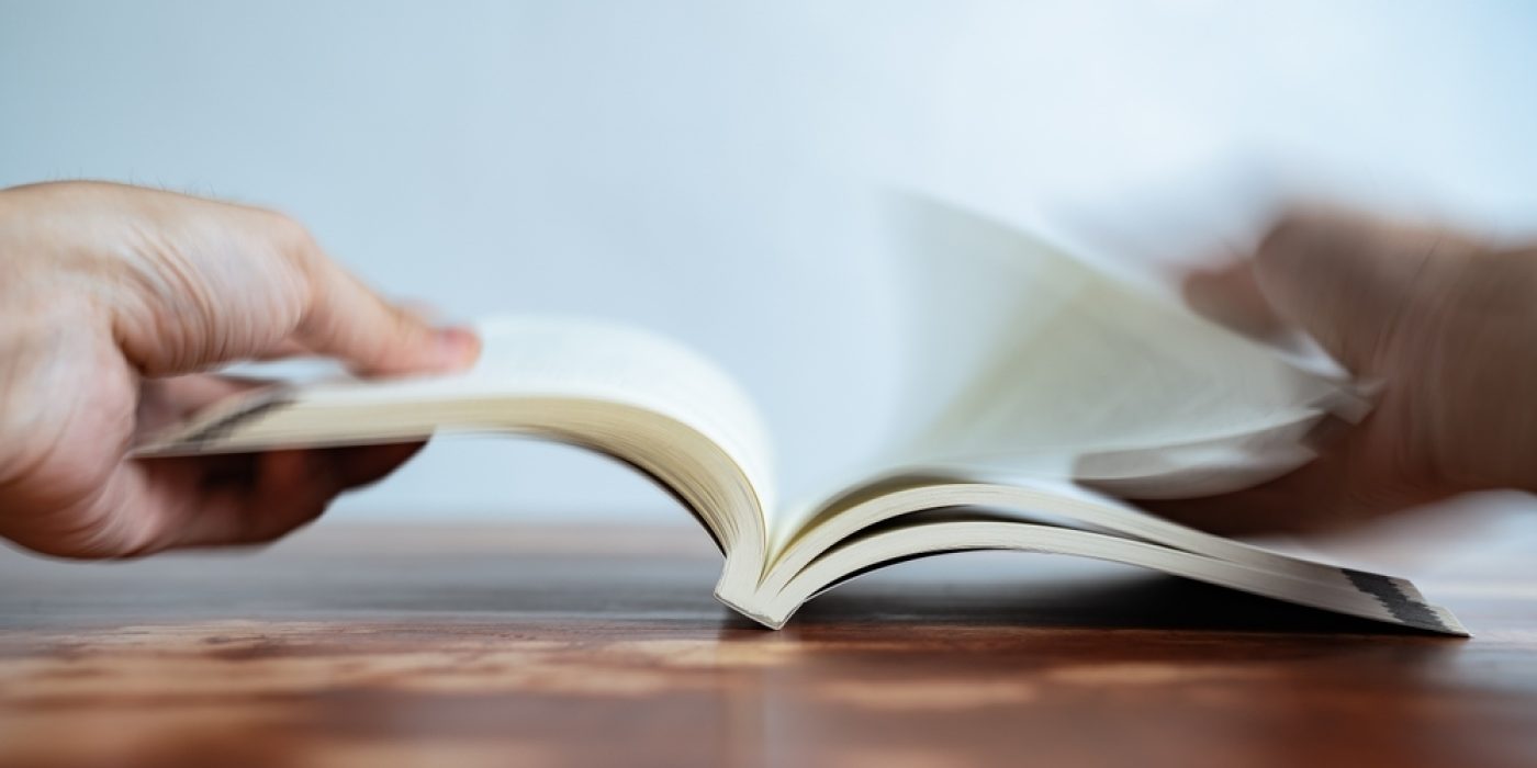 Pessoa lendo um livro com movimento de páginas, simbolizando leitura rápida em inglês.