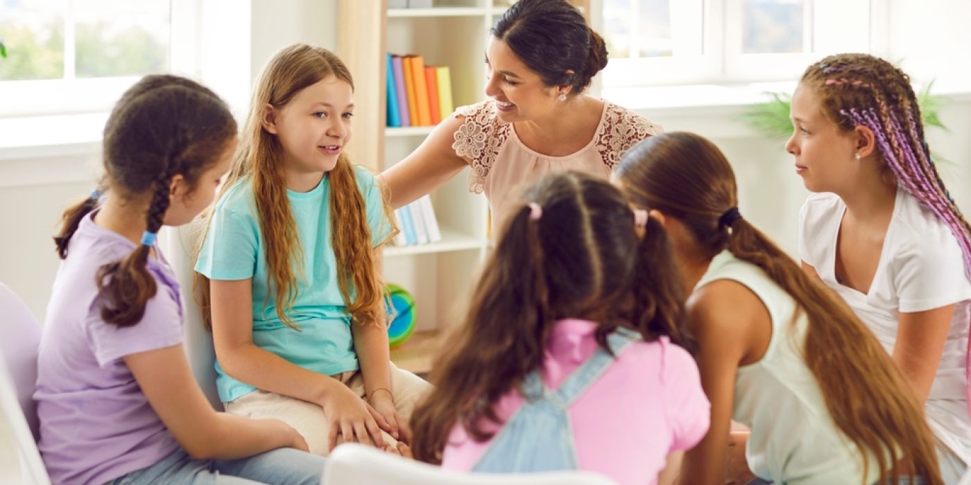 crianças em roda conversando com professora/psicóloga em uma sala