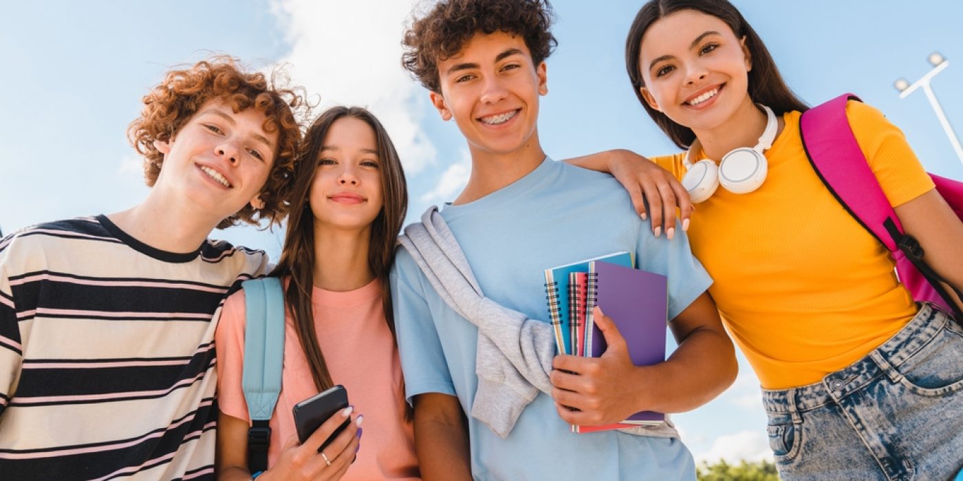 Quatro alunos do Ensino Médio sorriem para foto ao ar livre em dia ensolarado