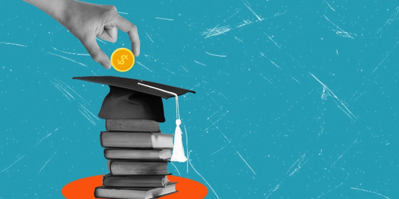 Mão coloca moeda sobre chapéu de formatura apoiado em pilha de livros, simbolizando o pagamento do aluno.