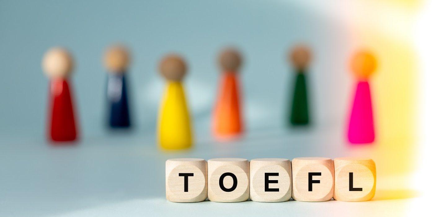 Blocos de madeira com a palavra TOEFL e figuras coloridas ao fundo.
