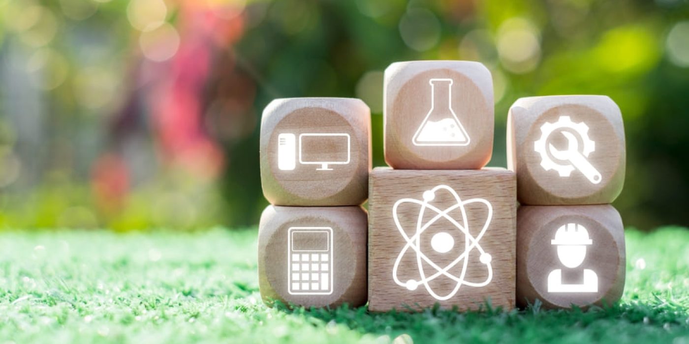 Blocos de madeira com ícones de ciência, tecnologia, engenharia e matemática, ilustrando a interdisciplinaridade.