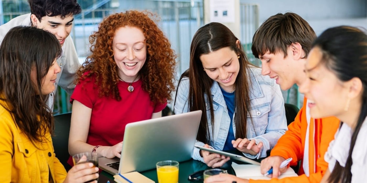 Estudantes trabalhando em grupo usando tecnologia, aplicando o método PBL para resolver problemas de forma colaborativa.