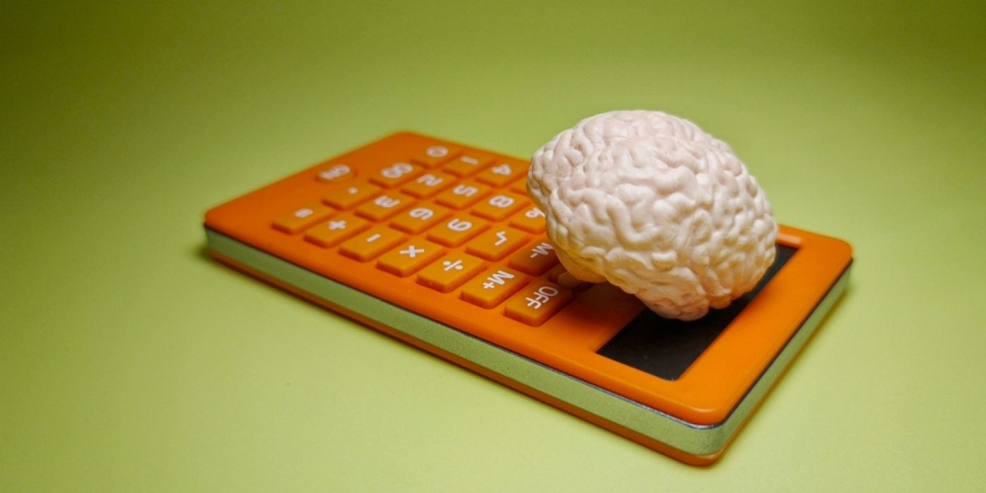 Calculadora com um cérebro em cima, simbolizando a relação entre lógica, raciocínio e resolução de problemas.