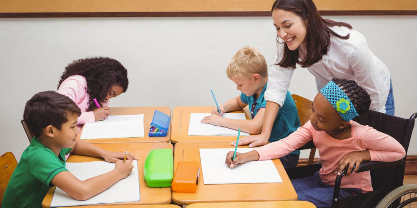 Professora fazendo o acompanhamento pedagógico de alunos em sala de aula.