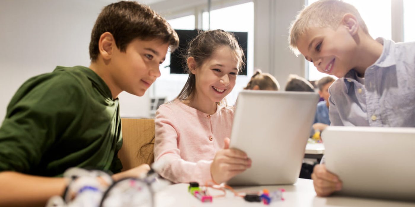 Crianças utilizando tecnologia em sala de aula como ferramenta de aprendizagem.